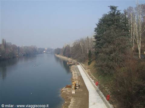River beside paved walkway, winter trees, hazy light, workers on the bank