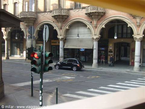Car stopped at red light beneath Bologna's historic porticoes