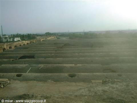 Ruins of ancient mud-brick granary vaults under hazy daylight