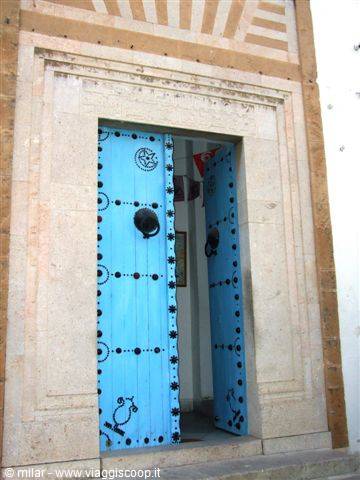 Blue wooden door painted with black studs, framed in carved stone