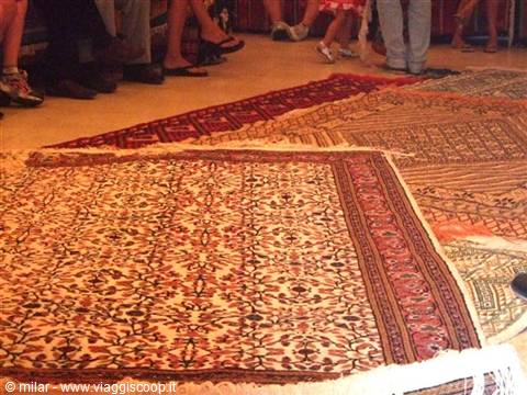 Ornate oriental rugs with floral patterns displayed on floor among visitors