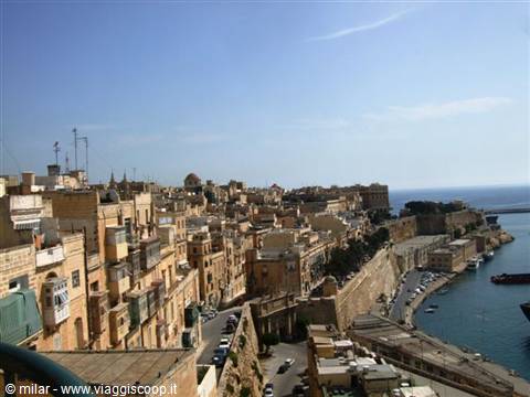 Golden stone fortified city overlooking the harbour under blue sky