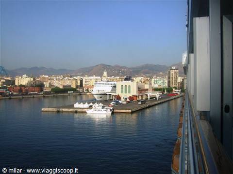Ferry ships docked at Palermo harbor, mountains and buildings under blue sky