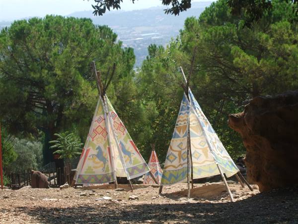 Two painted tipis with colorful patterns among pine trees and a valley