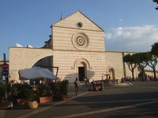 Tourists resting on the square before the stone facade with rose window