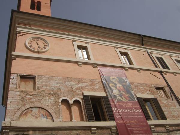 Pink building with clock and Pintoricchio exhibition banner, Spoleto
