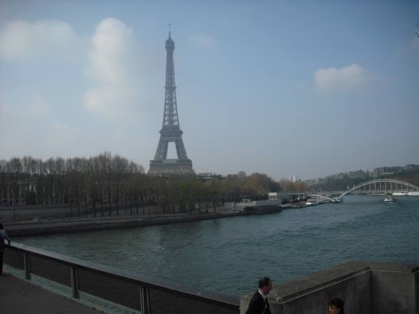 Passersby on the Seine embankment with the Eiffel Tower and a bridge