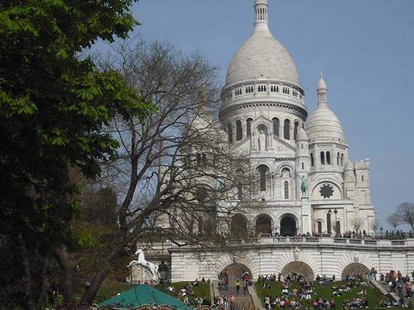 Sacré-Cœur basilica in Montmartre, tourists sitting on the lawn below