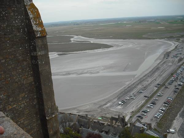 From Mont-Saint-Michel stone walls, the bay with exposed sands and parking lot