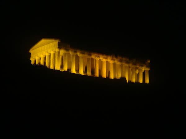Doric temple lit at night, golden columns glowing against the dark, Agrigento