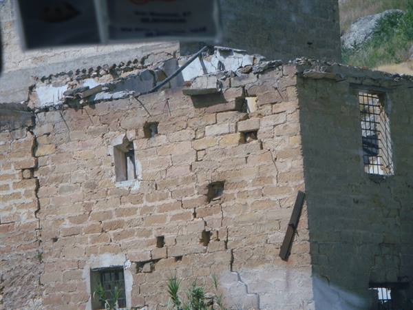 Dilapidated stone house with barred windows in daylight