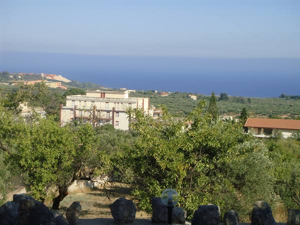 Trees and white houses on hills before the blue sea