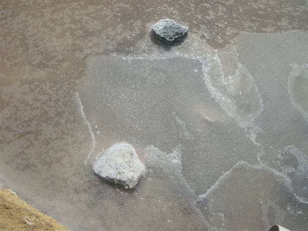 Two white salt-crusted rocks emerge from shallow crystal water