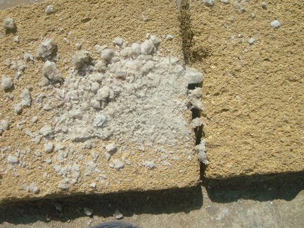 White salt crystals on yellow limestone blocks under harsh sunlight