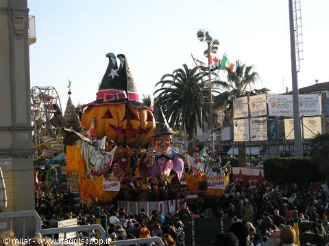 Carnival float shaped like a jack-o'-lantern with witch hats among the crowd