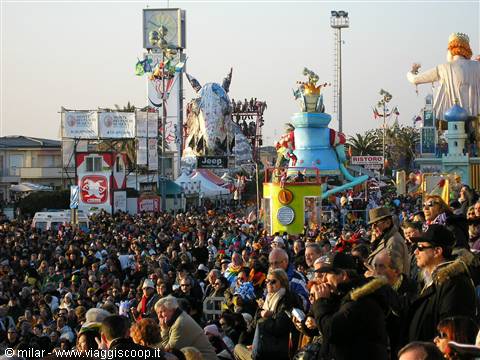 Crowd on Viareggio carnival promenade, colorful allegorical floats in afternoon light