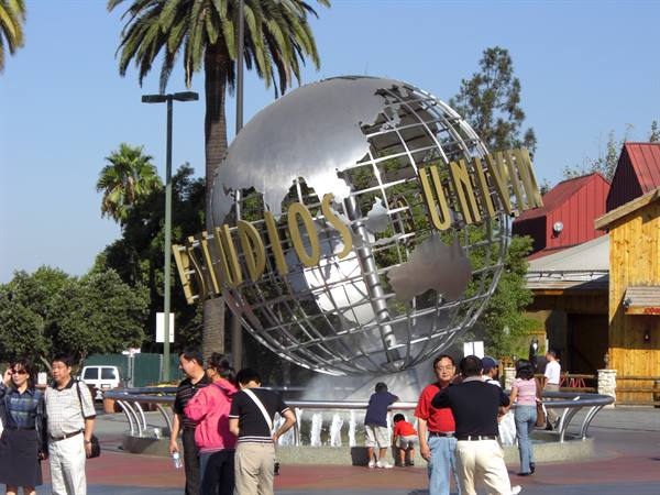 Tourists around the metallic Universal Studios globe among palms and fountains