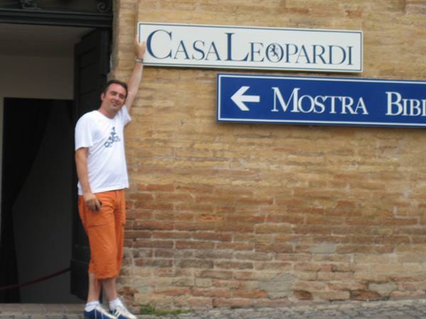 Man touching the Casa Leopardi sign on a brick wall in daylight