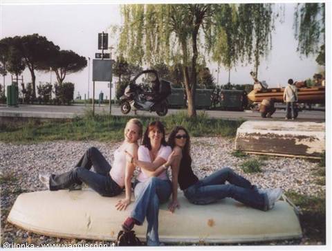 Three girls posing on an overturned boat on the gravel lakeside
