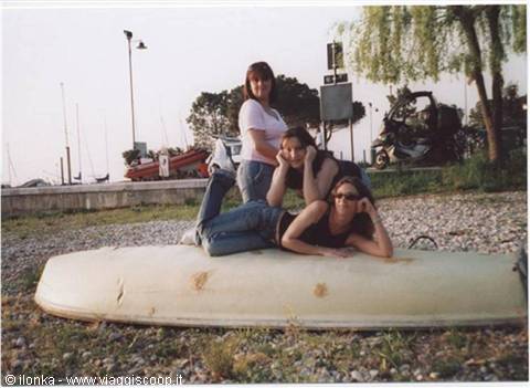 Three girls on an overturned old boat on the pebble beach