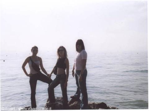 Three girls posing on a rocky outcrop in front of a hazy sea