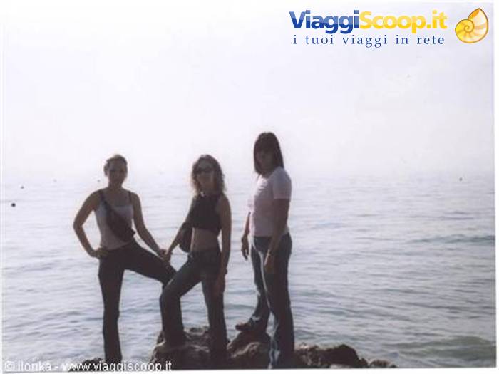 Three girls posing on a rocky outcrop in front of a hazy sea