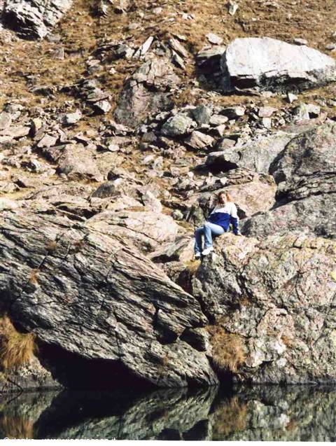 Woman sitting on granite rock by a mountain lake