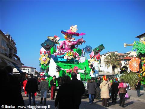 Colorful carnival float with masked figure, crowd watching along the street