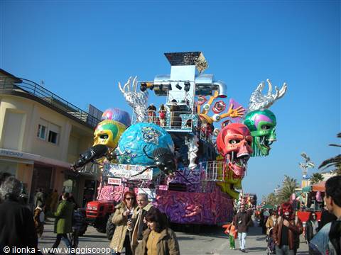 Colorful carnival float with giant masks parading through town streets