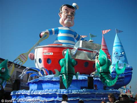 Carnival float with giant sailor on red boat among green fish