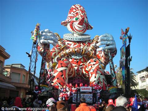 Carnival float with giant red-and-white papier-mâché clown towering over the crowd