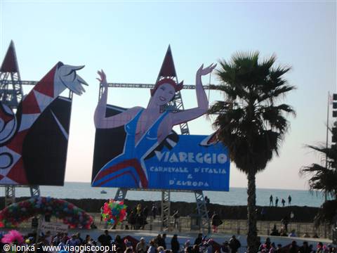 Viareggio Carnival: float with painted dancer, palm tree and crowd on the promenade