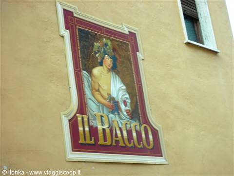 Painted sign of Bacchus holding grapes on an ochre wall