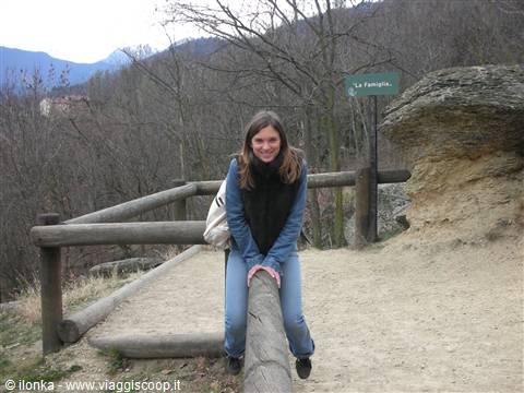 Girl sitting on a wooden log by a rock, La Fornace sign