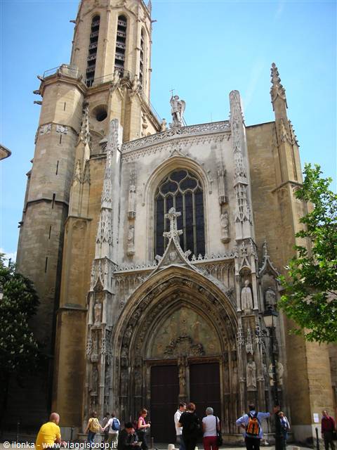 Tourists in front of the Gothic stone facade of Aix Cathedral