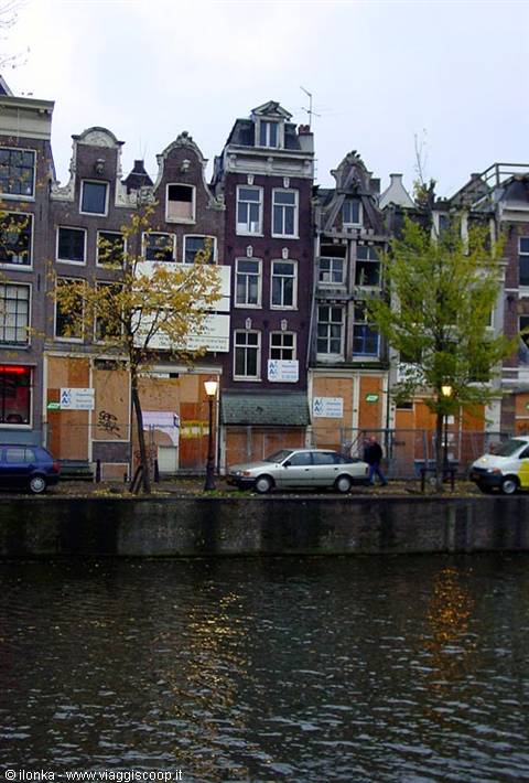 Canal houses in Amsterdam with stepped gables and cars parked along the water