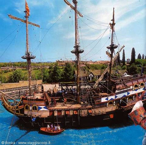 Wooden galleon moored with visitors on board, small yellow boat on turquoise water
