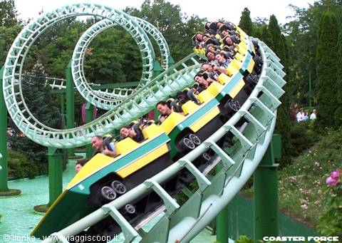 Yellow and green looping coaster train full of riders amid trees