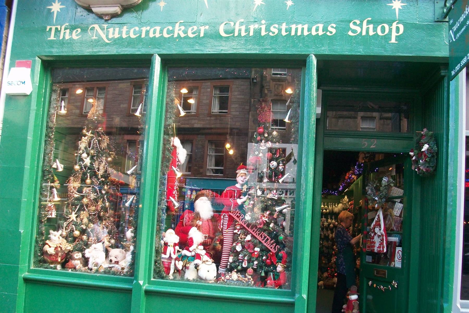 Green storefront of the Nutcracker Christmas Shop with decorated trees and Santa figures
