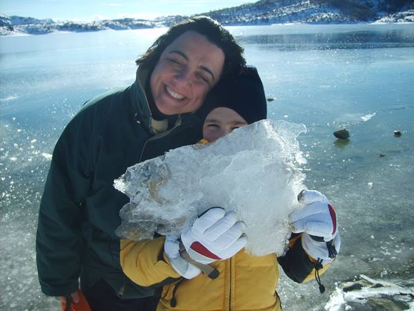 Woman and child smiling holding ice slabs by frozen lake