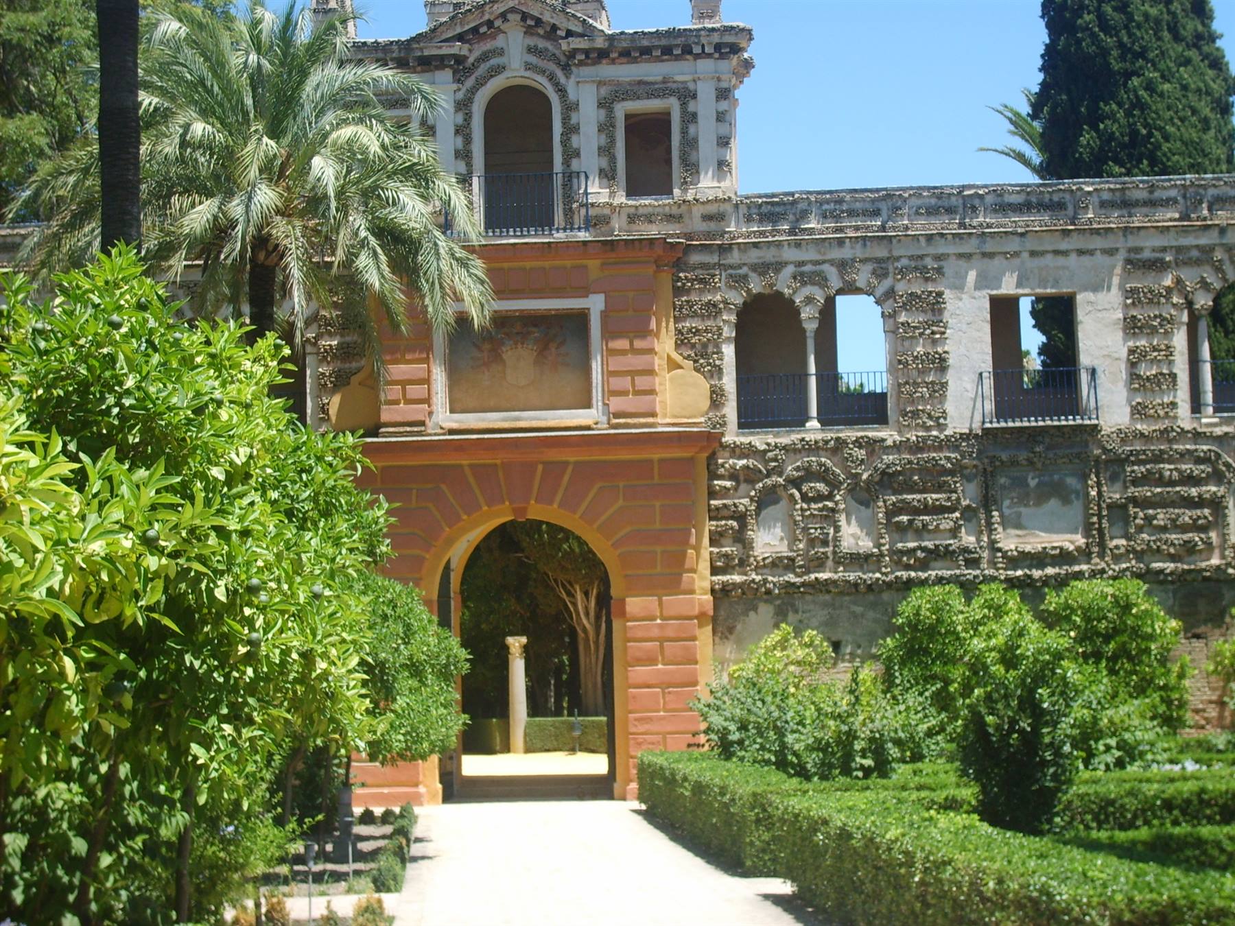 Gardens of the Alcázar of Seville, brick archway and green hedges in sunlight