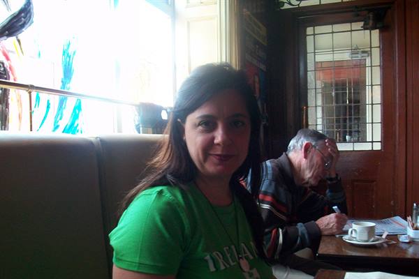 Woman in green shirt smiles in a pub, man writing at table