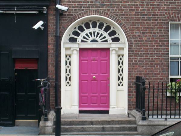 Bright pink Georgian door with white fanlight on red brick facade, Dublin