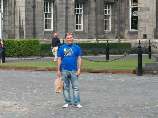 Tourist in blue t-shirt holding paper bag on Trinity College cobblestones