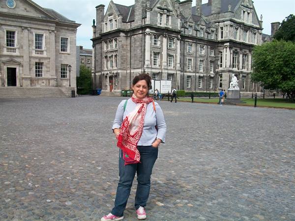 Woman with red scarf in front of Trinity College Dublin stone buildings