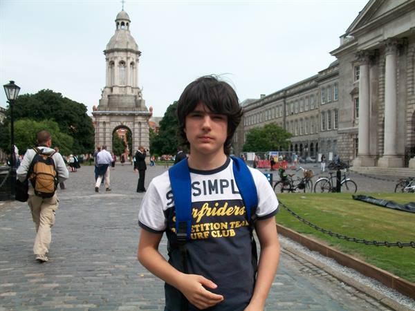 Boy with blue backpack in front of the Trinity College Dublin campanile
