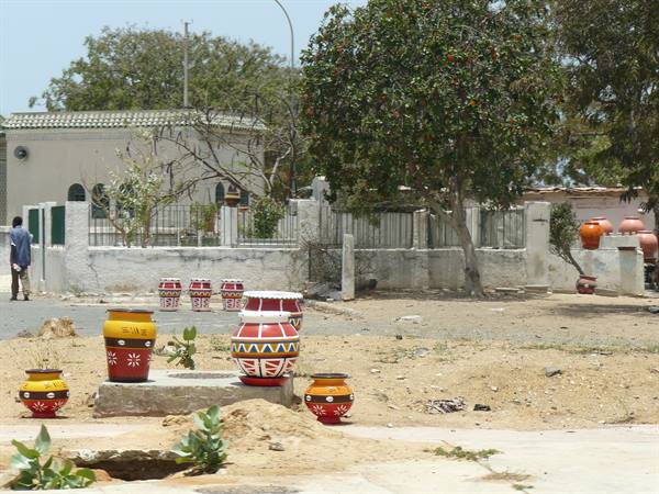 Painted red and yellow clay pots lined along a sandy street