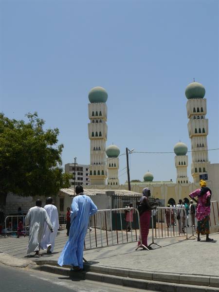 Worshippers in boubous walk past the green minarets of Dakar's Great Mosque