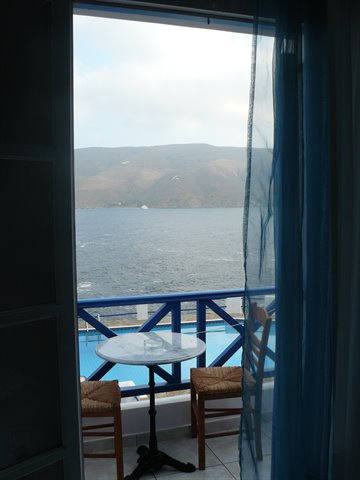 Table with two straw chairs on blue balcony overlooking the sea