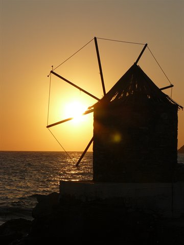 Stone windmill silhouetted against the setting sun over the sea